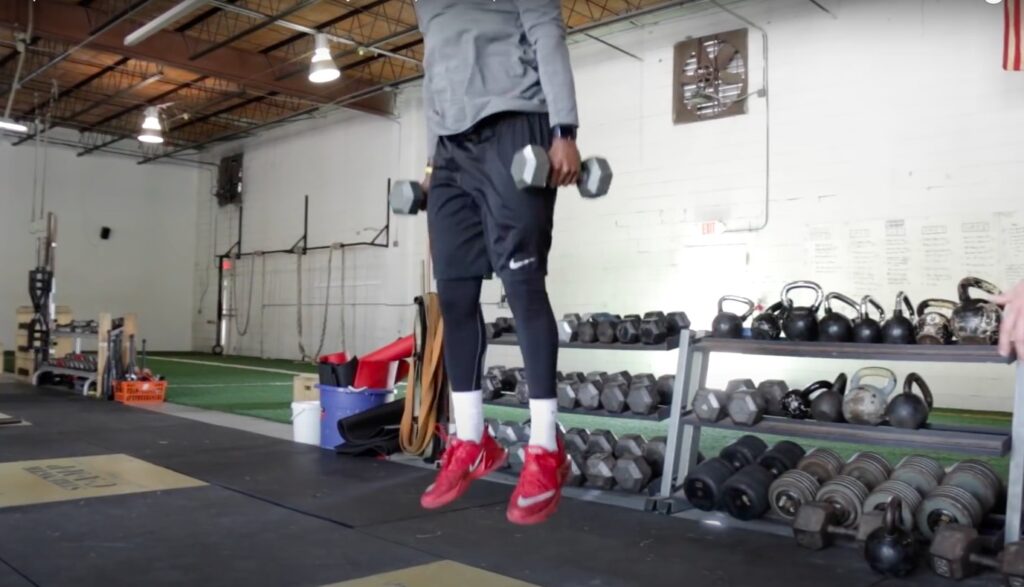 Athlete performs weighted dumbbell squat jumps